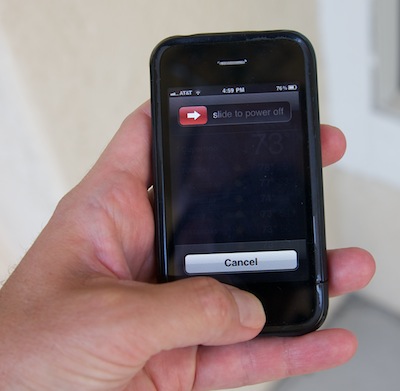 photo of holding an Apple iPhone and pressing the home button to force quit an application